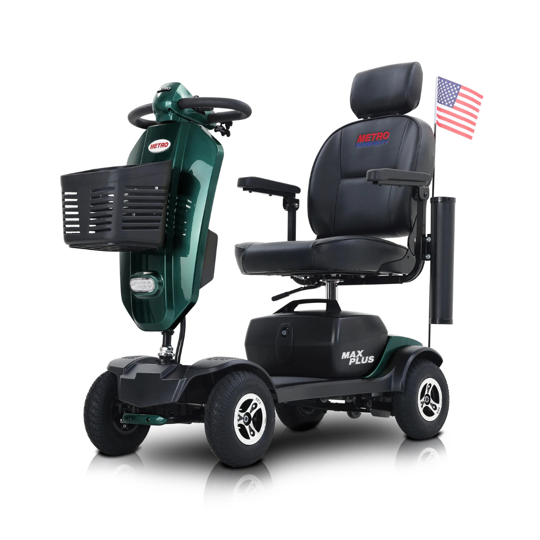 A green metro Mobility MAX Plus Scooter with four pneumatic tires, a black seat labeled METRO, front basket, and a small American flag on the back. MAX PLUS appears on the base.